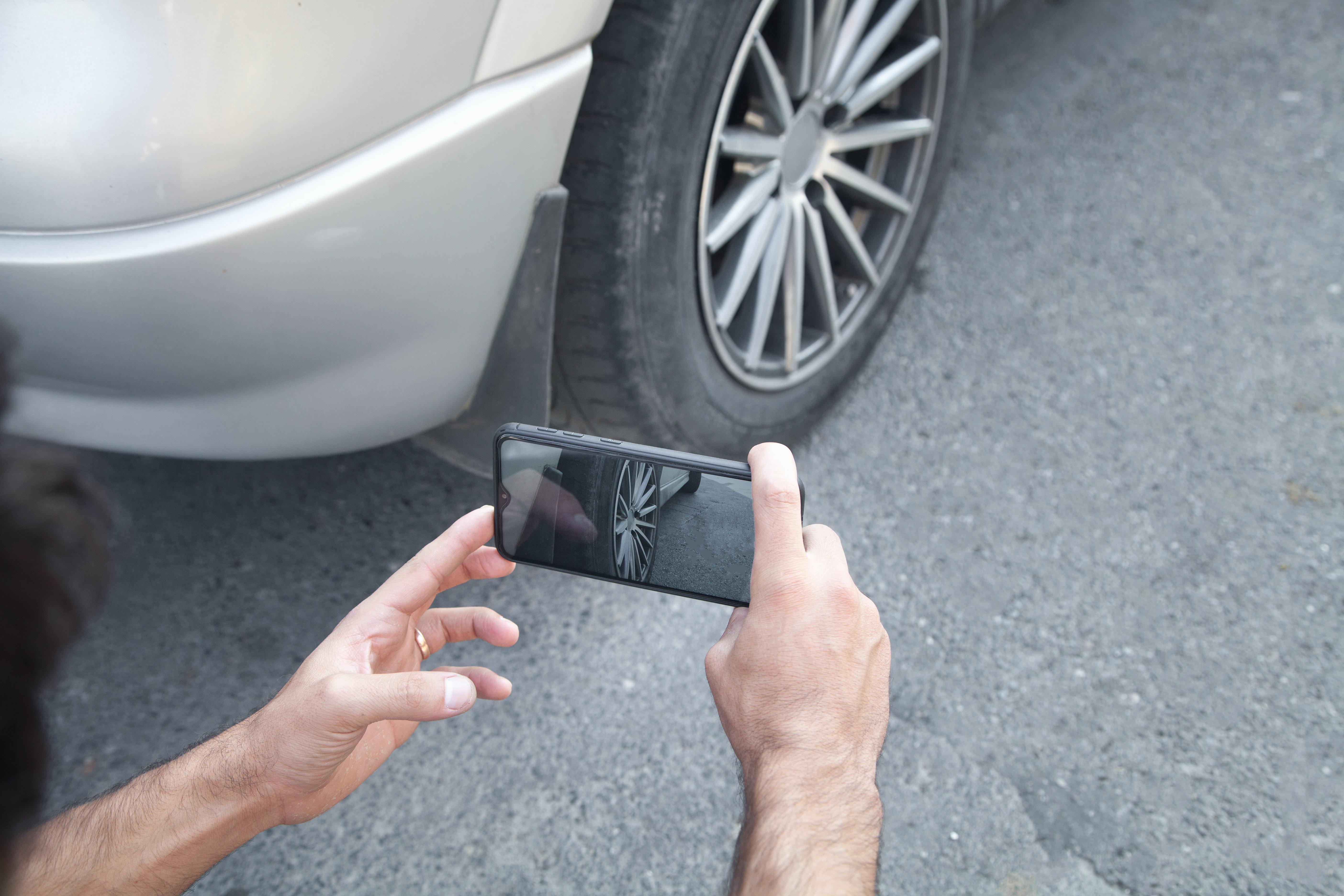 Persona haciendo una foto a la rueda de un coche con su teléfono